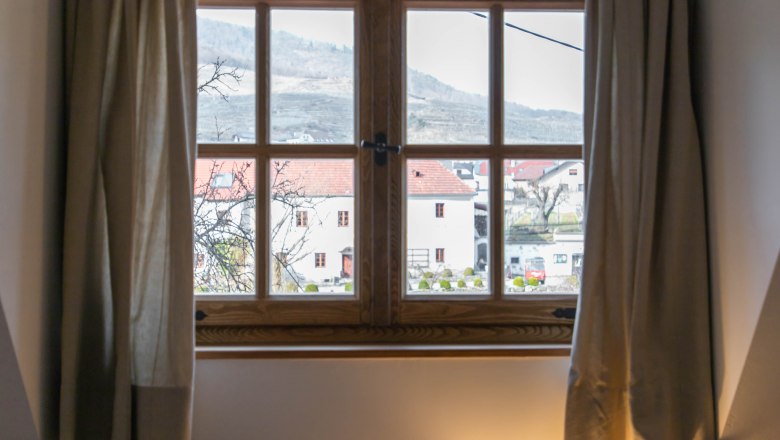 View from a window of a rural scene with houses and hills in the background.
