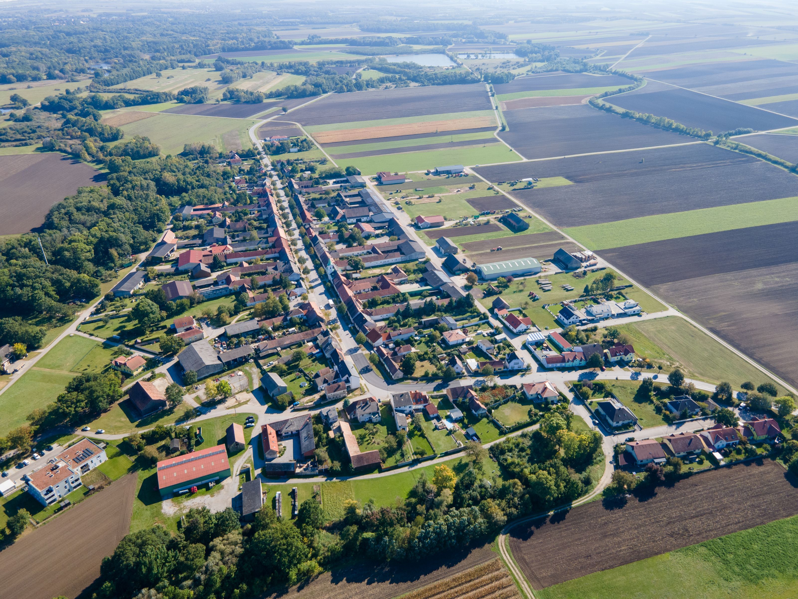 Aerial view of the town of Weiden an der March, showing the village center, fields, and strips of forest in the surrounding area.