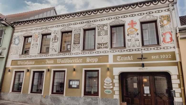 Fa&ccedil;ade of a traditional inn with decorative paintings and the lettering "Zum Waldviertler Sepp" in Schrems.