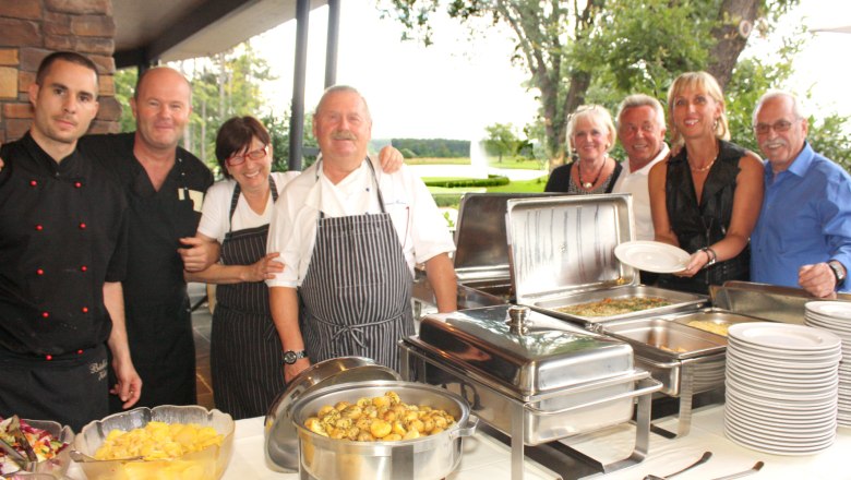 Group of people in a restaurant next to a buffet of food.