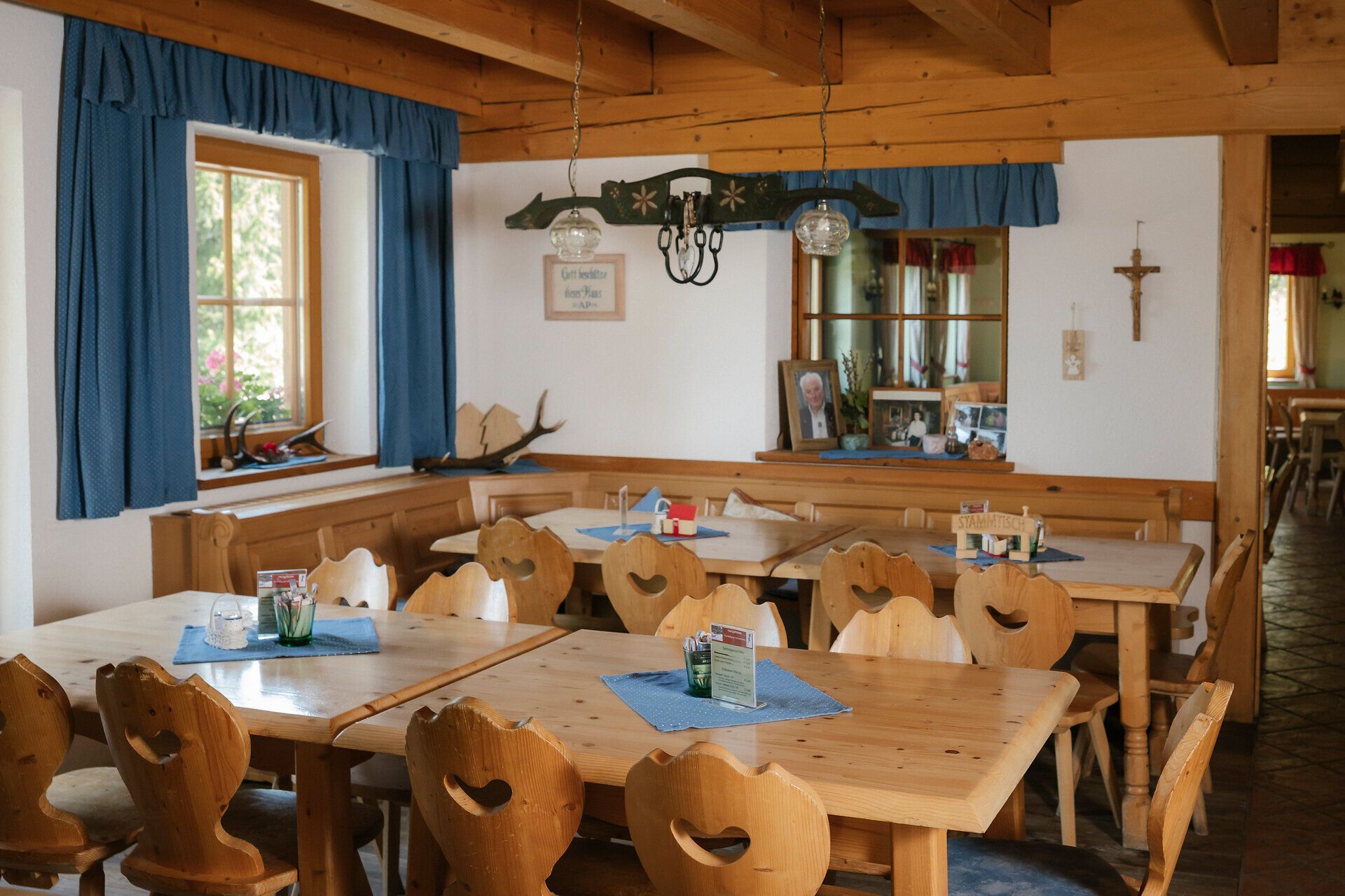 Dining room with heart-shaped chairs and blue curtains at the Hengsthütte on Schneeberg