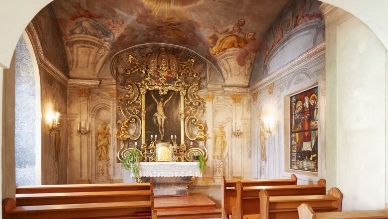 Interior view of a chapel with an elaborately decorated altar and frescoes on the ceiling.