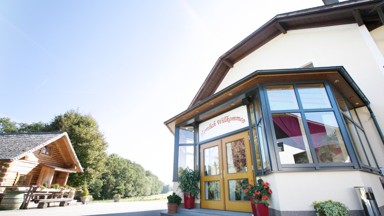 Entrance to a building with glass veranda and "Welcome" sign.