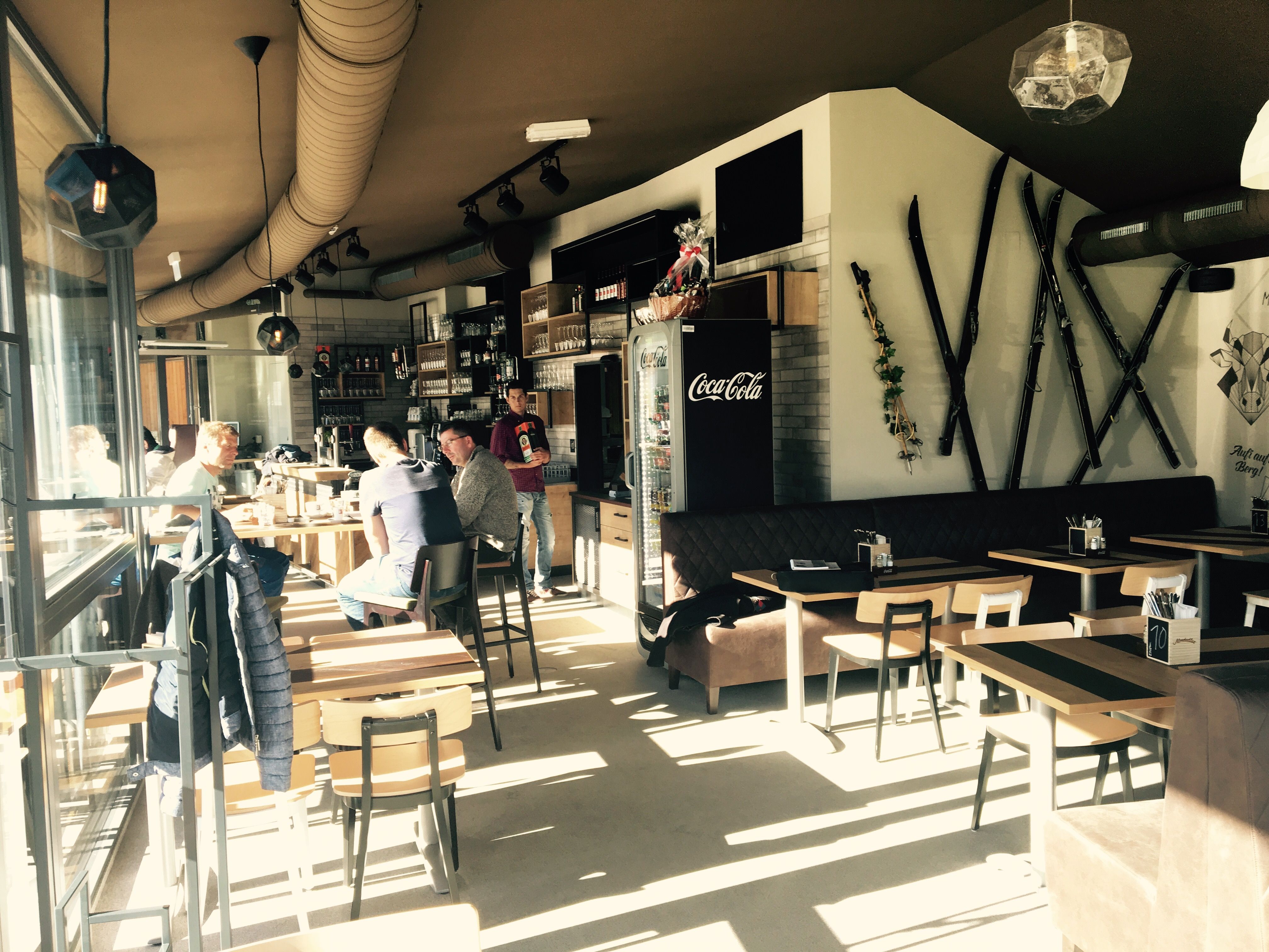 Interior view of a café with wooden furniture and skis on the wall.