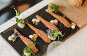 Gourmet dish with salmon, herbs and flowers served on a slate plate.