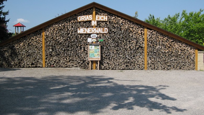 Exterior view, © Gasthof Skilitz Woodpile with sign 'Griaß Eich im Wienerwald'.