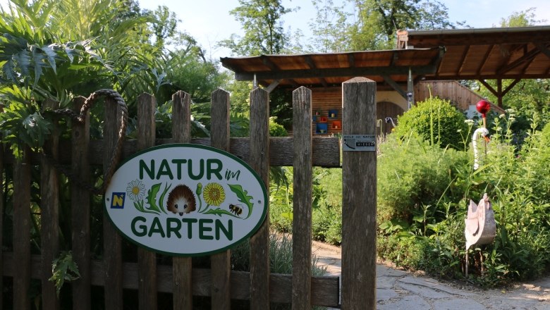 Entrance to a garden with a sign 'Nature in the garden'.