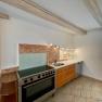 Modern kitchen with stove, wooden cupboards and tiled floor.