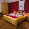 Cozy guest room with double bed, wooden furniture and red wall.
