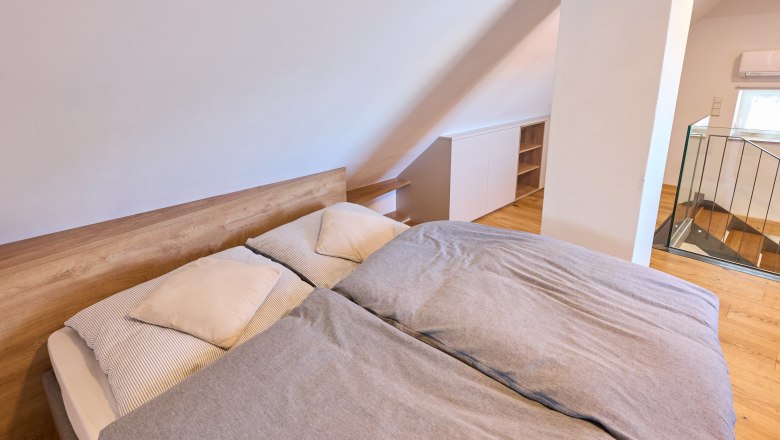 Attic bedroom with double bed and wooden floor.