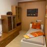 Single room with wooden furniture, single bed and decoration.