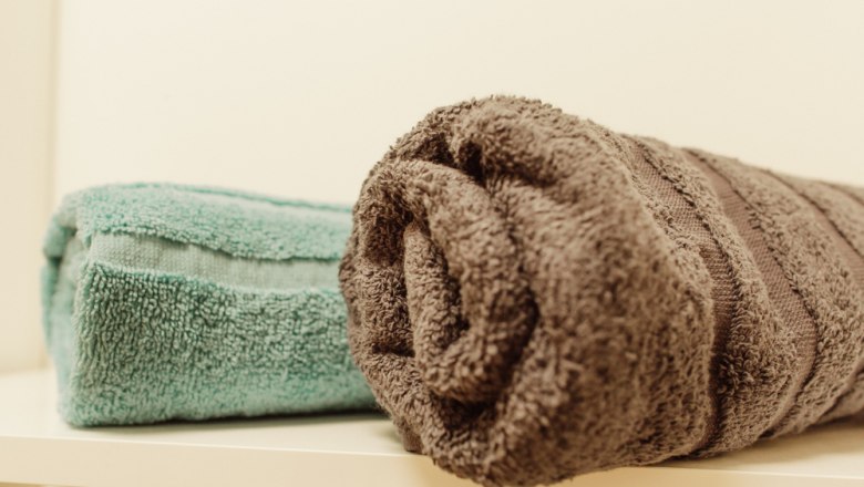 Two towels, one turquoise and one brown, lie on a shelf.