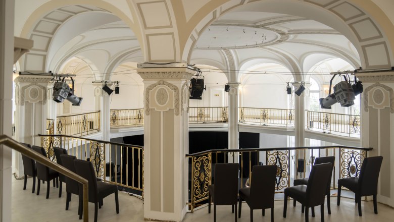 Interior view of an elegant hall with arches and golden railings.