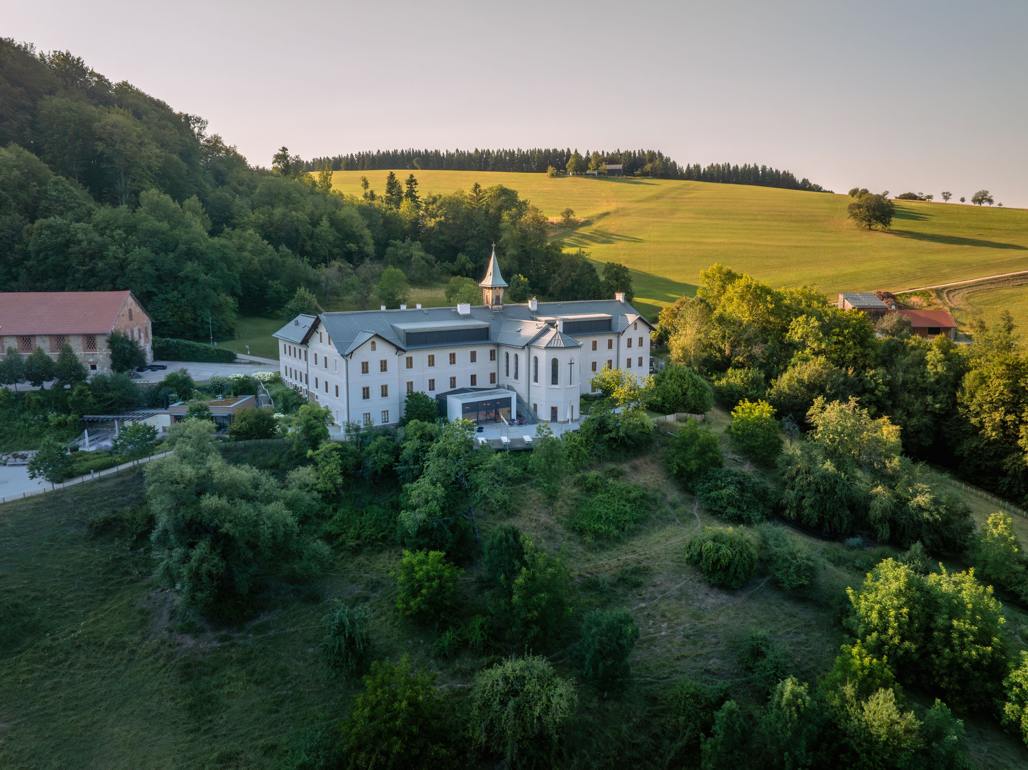 Aerial view of a large white building in a green landscape.