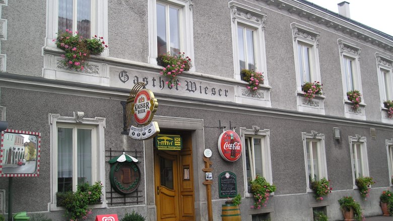 Wieser Inn, © zVg Facade of the Wieser inn with flower boxes and advertising signs.
