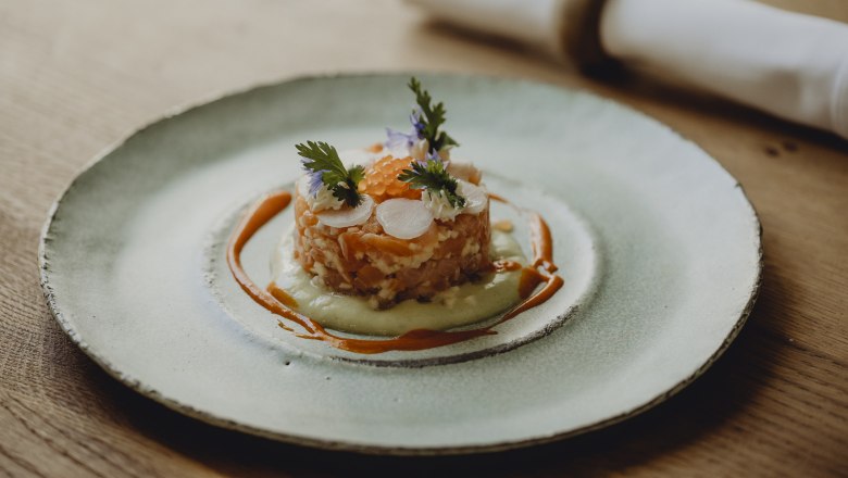 Gourmet dish on a plate decorated with salmon, herbs and sauce.