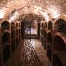 A wine cellar with brick vaults and wine bottles on shelves.