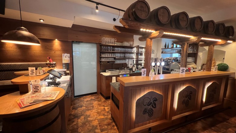 Rustic bar with wooden paneling and beer barrels as decoration.