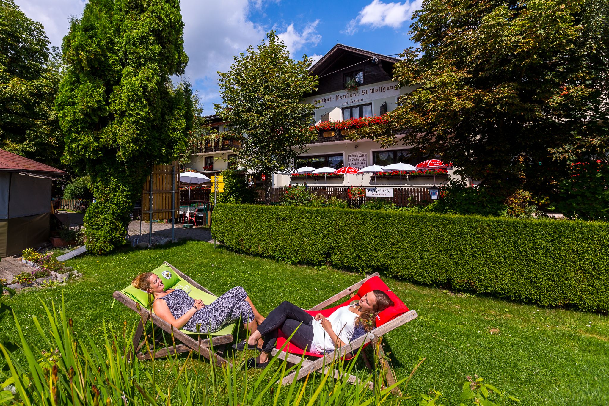 Two women relaxing in deckchairs in the garden of an inn.