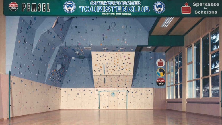 Interior view of a climbing hall with a blue climbing wall and colorful holds.